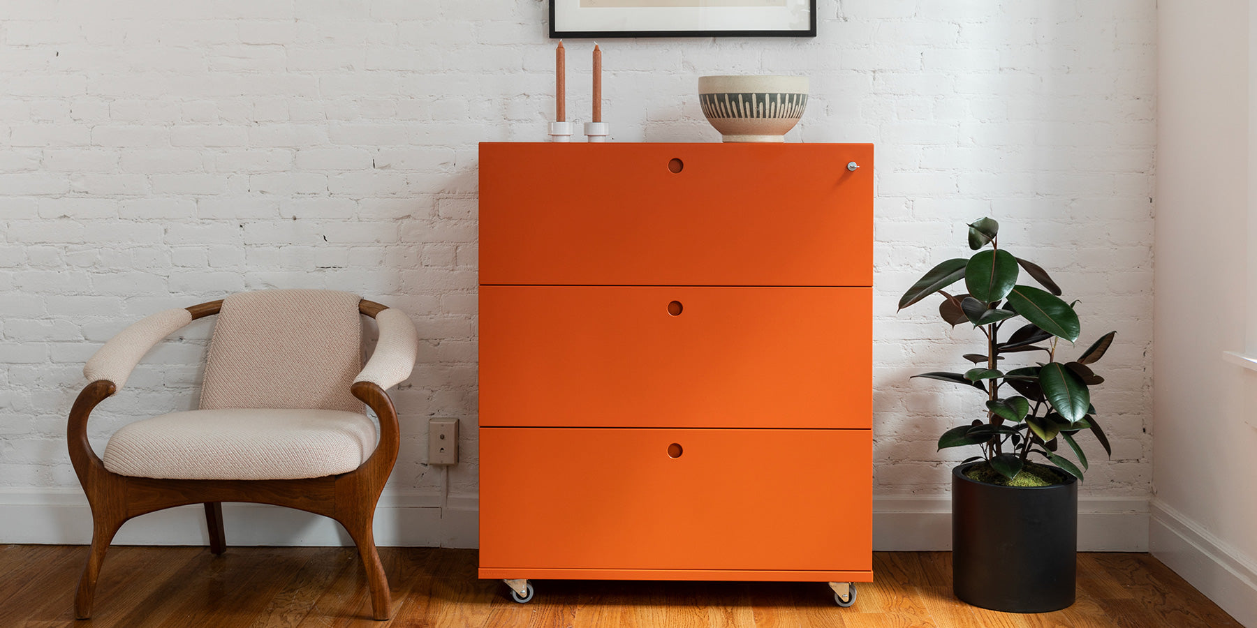 Heartwork Building Block lateral file with three drawers in orange in home setting next to an armchair