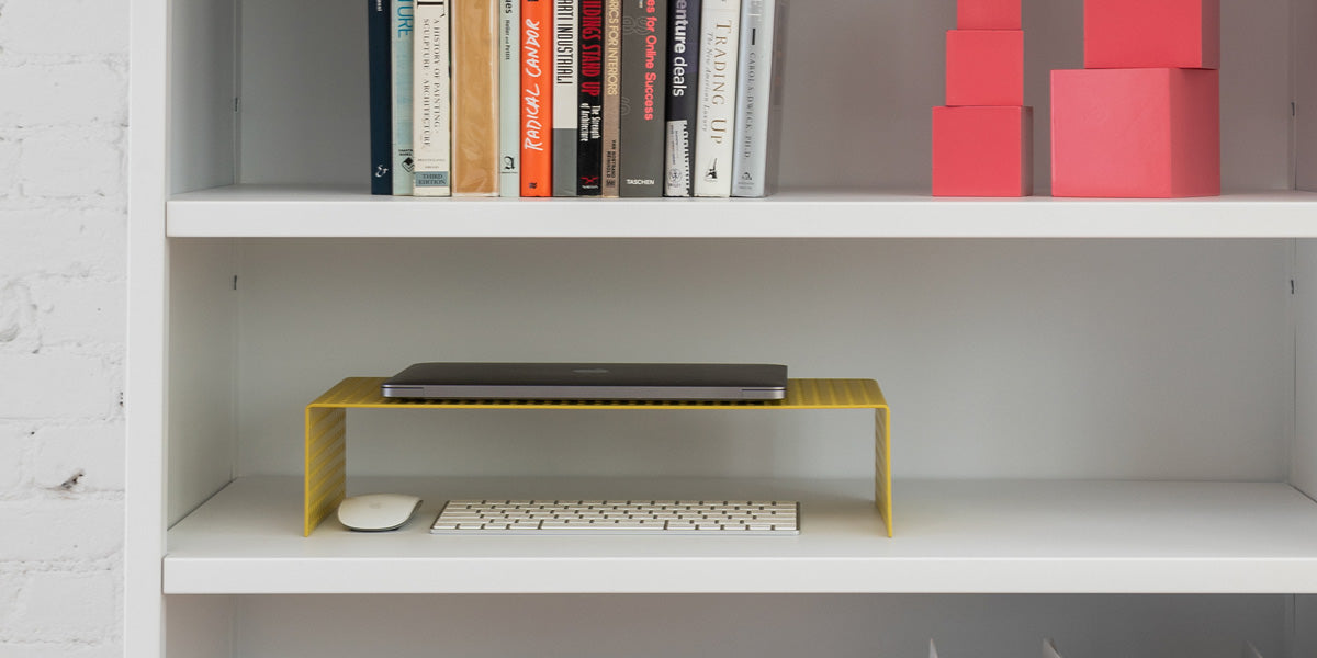 Heartwork Monitor Stand in yellow on shelf with laptop, keyboard and mouse